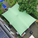 Close-up van een Forest Green Stretchtent (7,5x10 meter) op locatie bij vanBos Barneveld. De tent heeft een rijke groene kleur en is strak gespannen, geschikt voor evenementen en buitengebruik. De omgeving is goed zichtbaar met de tent in focus, waarbij de vorm en het materiaal van de tent duidelijk naar voren komen.