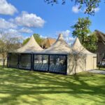 Beige pagodetent van 5×5 meter met hoog puntdak en vier zijwanden, met sterk aluminium frame en PVC doek, geschikt voor feestelijke, particuliere of zakelijke buitengelegenheden.