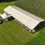 Zandkleurige aluhal tent te huur met doorzichtige zijwanden voor bruiloft, festival of bedrijfsfeest vanbos tenten