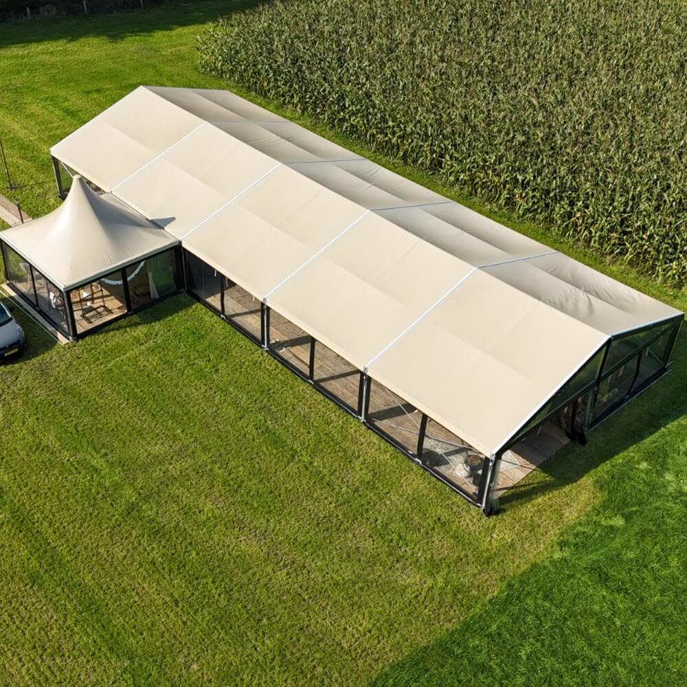 Zandkleurige aluhal tent te huur met doorzichtige zijwanden voor bruiloft, festival of bedrijfsfeest vanbos tenten