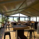 Zandkleurige aluhal tent huren met doorzichtige zijkanten voor bruiloft, huwelijk of bedrijfsfeest vanbos tenten