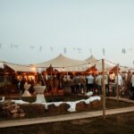 Stretchtent met zandkleurig doek, houten palen en scheerlijnen vanbos tenten
